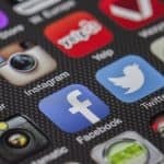 Smartphone scherm met social media app iconen zoals Facebook, Twitter en Instagram.