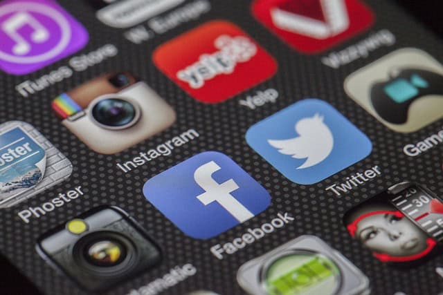 Smartphone scherm met social media app iconen zoals Facebook, Twitter en Instagram.